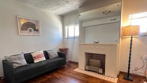 Una sala de estar con un sofá verde oscuro, una chimenea y una lámpara.