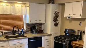 A kitchen with white cabinets, a wooden island, and a stove.