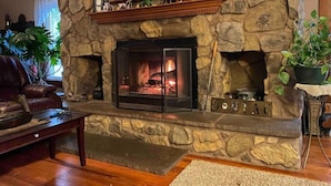 A stone fireplace with a TV above it, a leather sofa, and a coffee table in a living room.