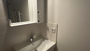 Une salle de bain avec un lavabo blanc, un miroir et un porte-serviettes.