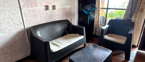 A room with a black sofa, a black armchair, and a small table.