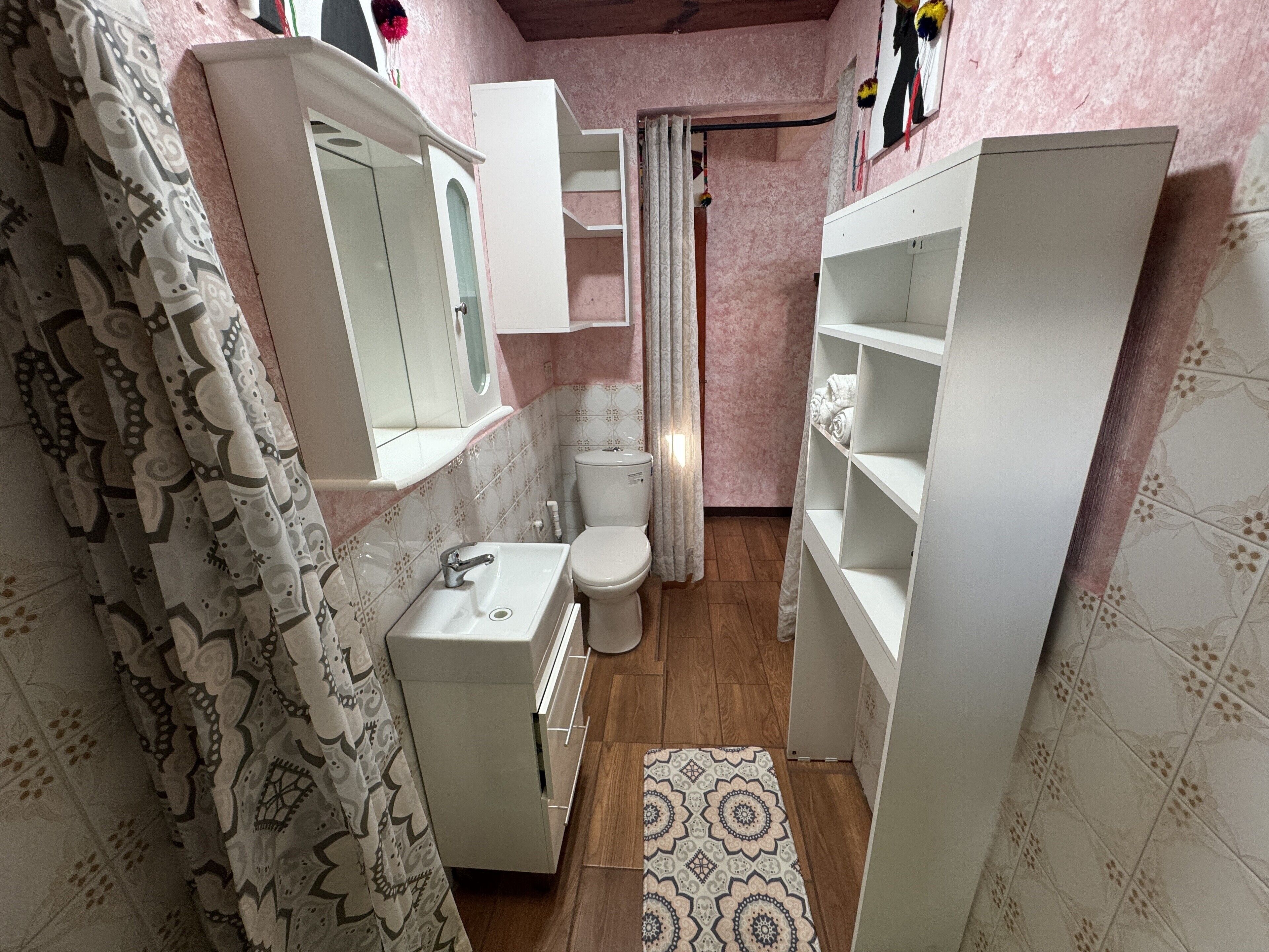 Un baño con lavamanos, inodoro y estantería abierta.
