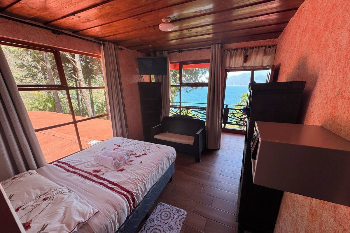 A bedroom with a bed, a chair, a desk, and a TV.