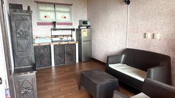 A compact living space with a kitchenette, a sofa, a small table, and a decorative cabinet.