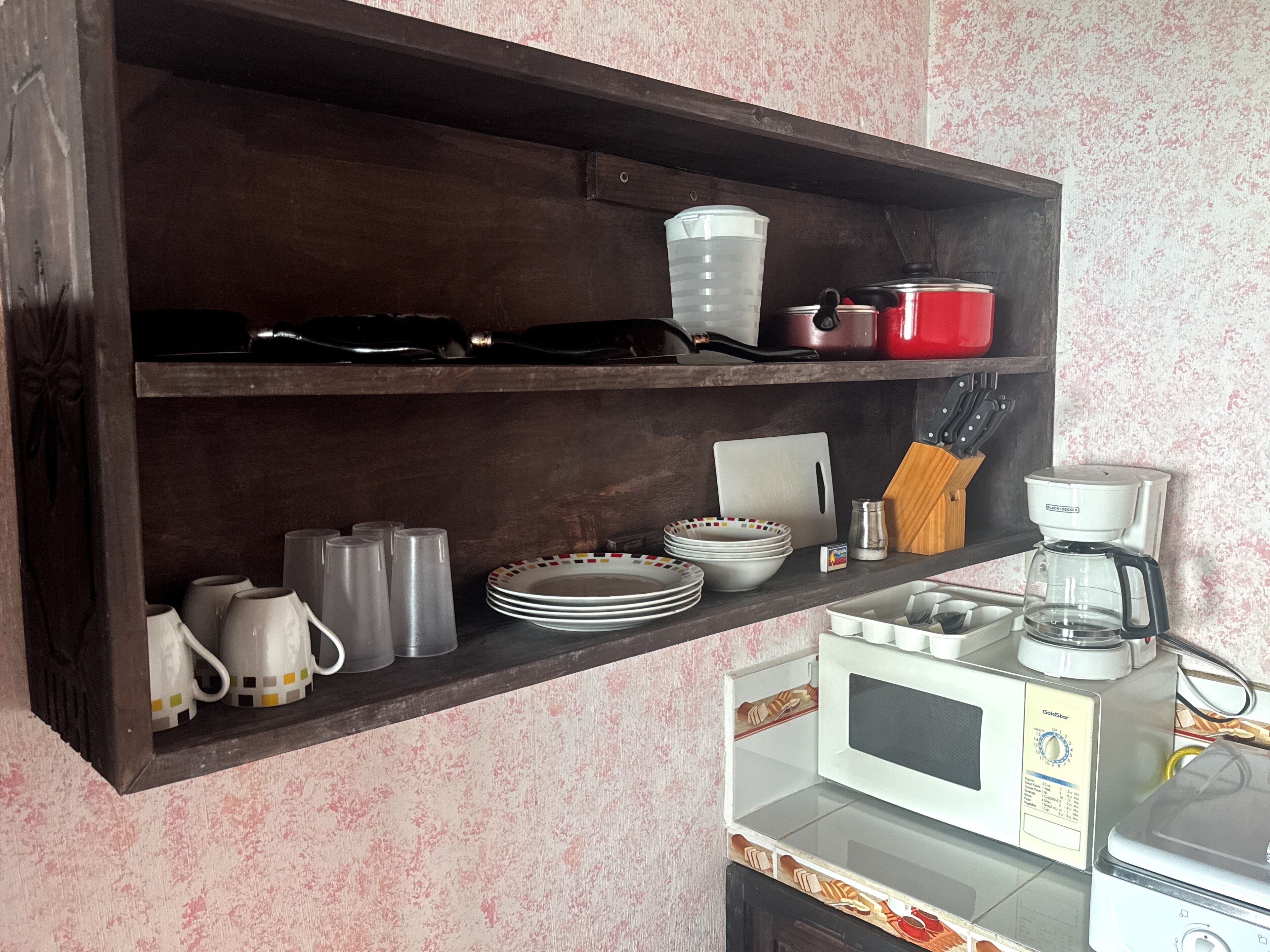 Una cocina con microondas, cafetera y distintos utensilios en la encimera.