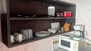 A kitchen with a microwave, coffee maker, and various utensils on the counter.