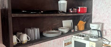 Una cocina con microondas, cafetera y distintos utensilios en la encimera.