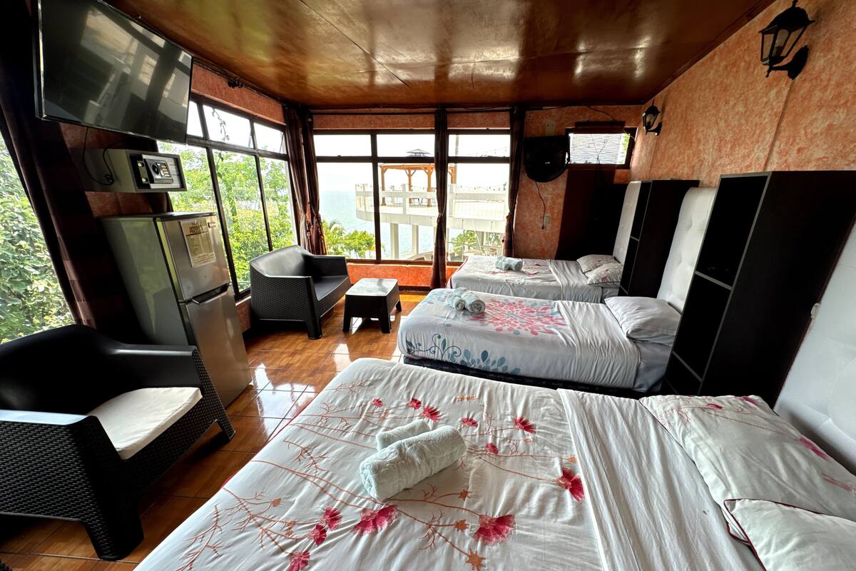 A hotel room with two beds, a sofa, a small table, and a TV.