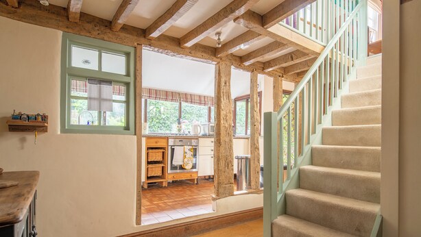 A rustic kitchen with wooden beams, a wooden counter, and a view to the outside. - Tegfan – Fairytale Cottage on Dedham High Street (Colchester)