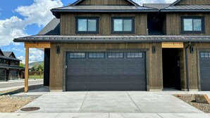 Une maison à deux étages avec une porte de garage sombre, un porche couvert et une allée.