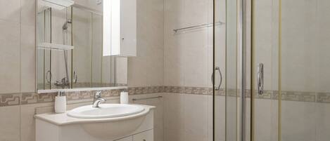 Une salle de bain moderne avec une douche à parois de verre, un lavabo blanc et un grand miroir.
