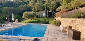 Ein Pool mit Steinfliesen, Liegestühlen und einer Steinwand.