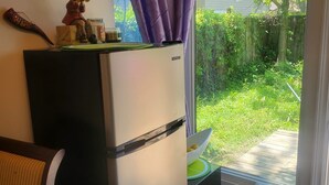 A kitchen with a refrigerator, a dining table, and a window with purple curtains.