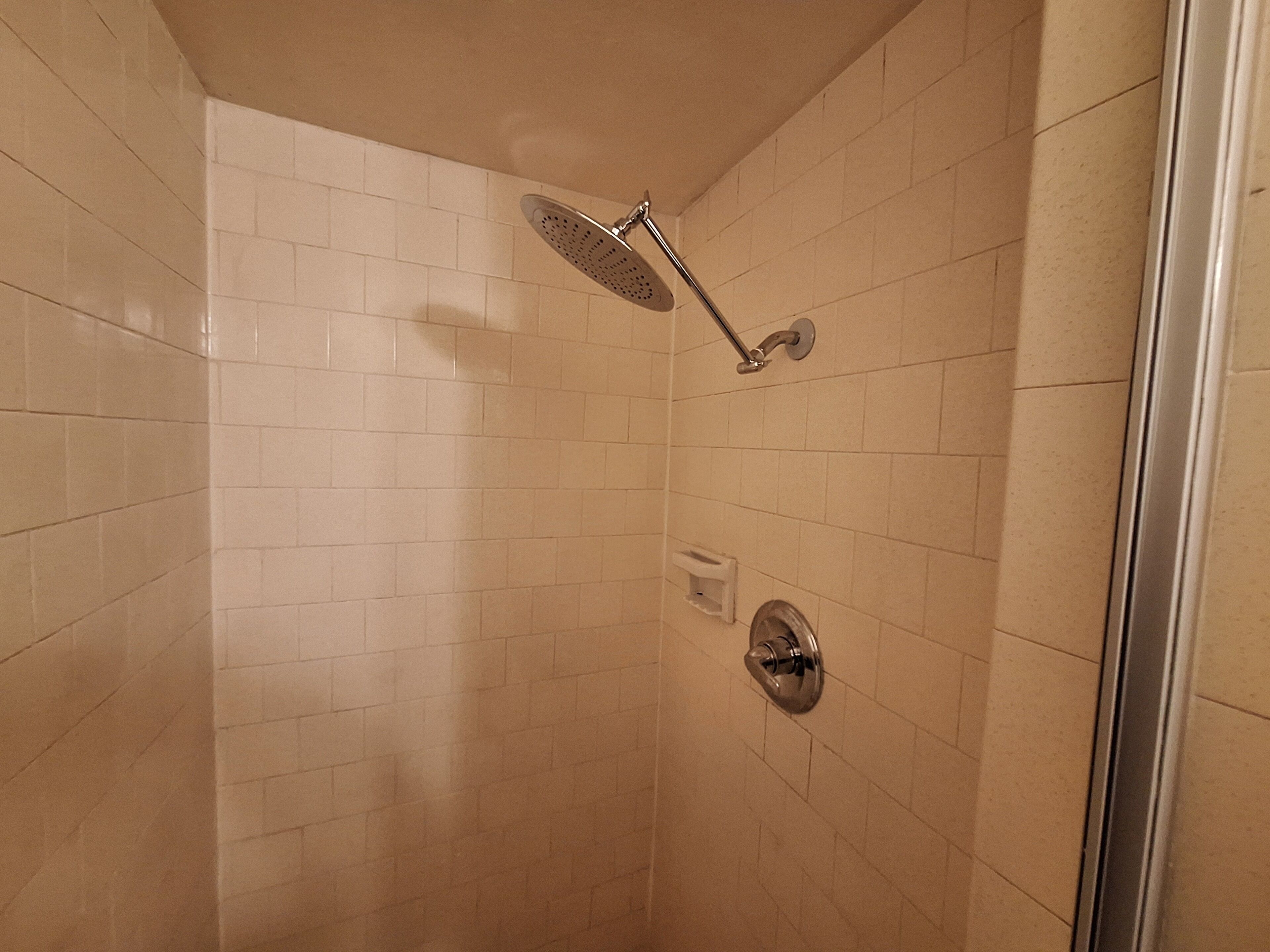 A shower with a handheld showerhead and a wall-mounted control valve.