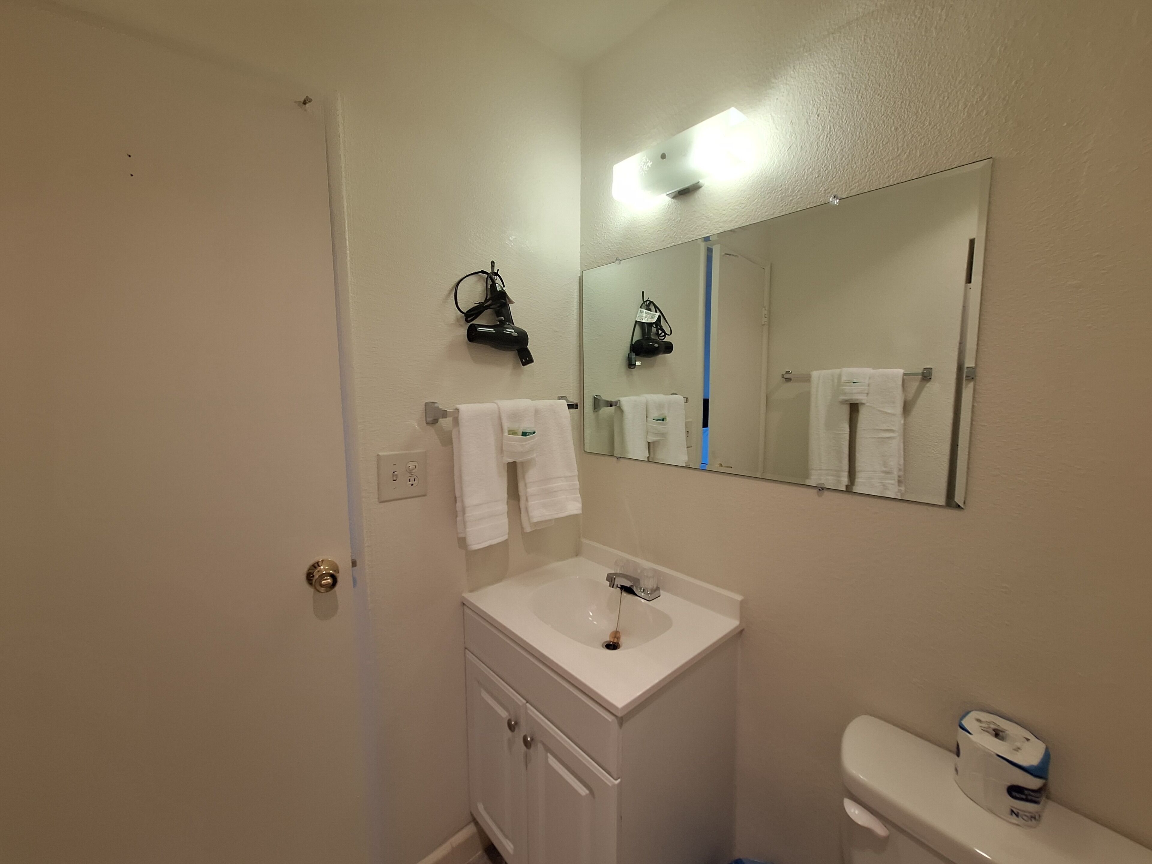 A bathroom with a white sink, a mirror, a towel rack, and a toilet.