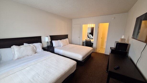 A hotel room with two beds, a desk, a chair, and a mirror. - Leisure Lodge Motel (Grants)