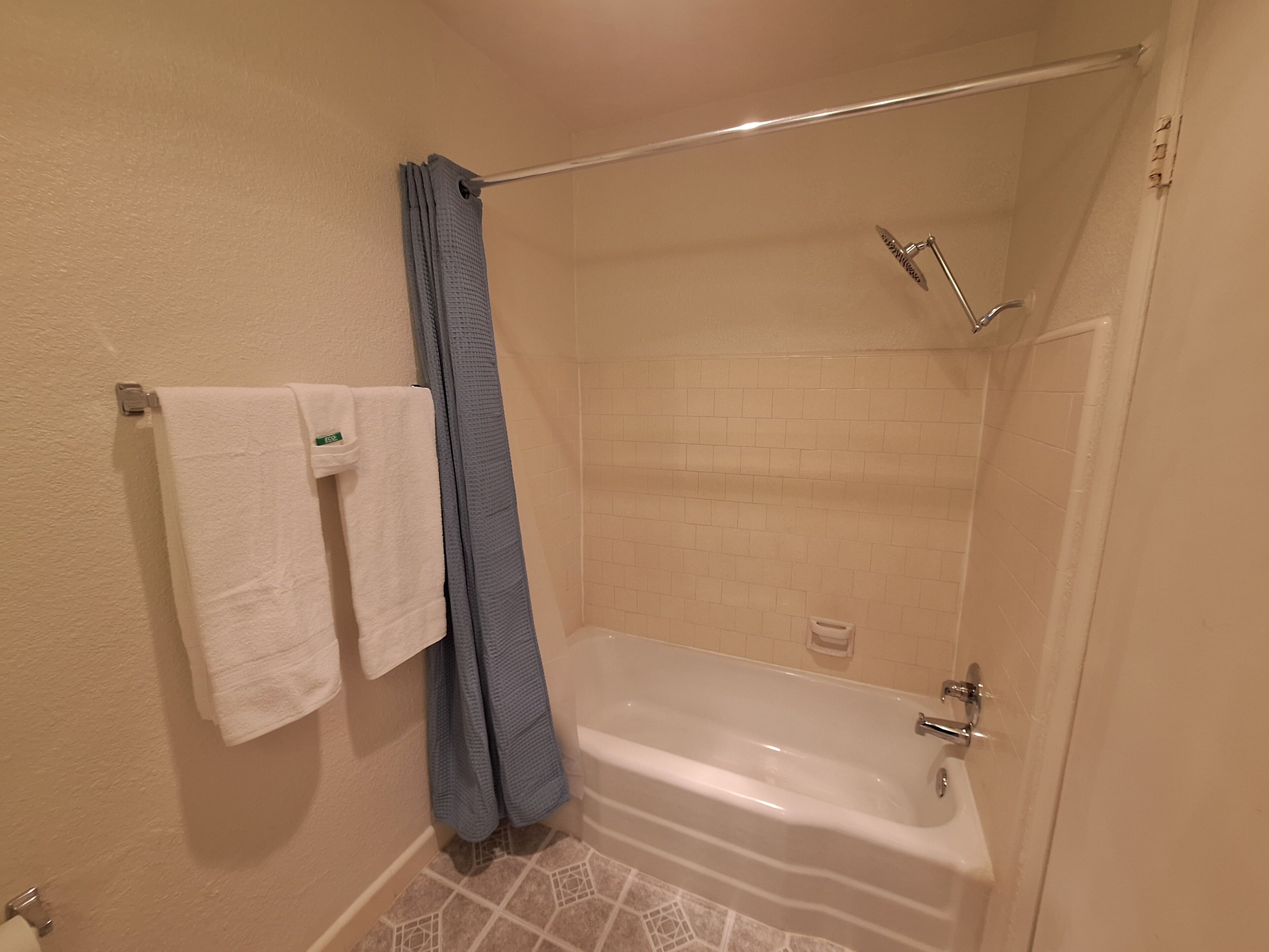 A bathroom with a bathtub, a shower, and a towel rack with two towels.