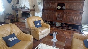 A cozy living room with leather armchairs, a wooden cabinet with decorative items, and a fireplace. - House for 10 people in Bois du Kador – surrounded by nature (Crozon)