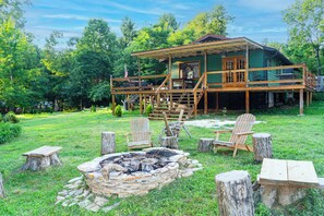 Eine Hütte mit einer Terrasse, einem Feuerkorb und Sitzgelegenheiten im Freien.