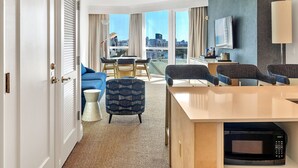 Una habitación de hotel moderna con un ventanal grande, un comedor y una kitchenette.