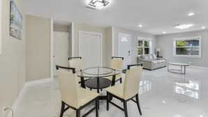 A modern living room with a glass dining table, beige chairs, a sofa, and a coffee table. - 3/2 Cozy and Stylish Poolside Home (St. Petersburg)