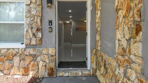 A stone exterior with a glass door entrance, a window, and a small outdoor area with a doormat. - 3/2 Cozy and Stylish Poolside Home (St. Petersburg)