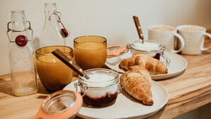 A breakfast setting with croissants, a glass of coffee, and jars of jam and honey.