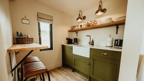 A compact kitchen with a wooden table, a bench, green cabinets, and a window.