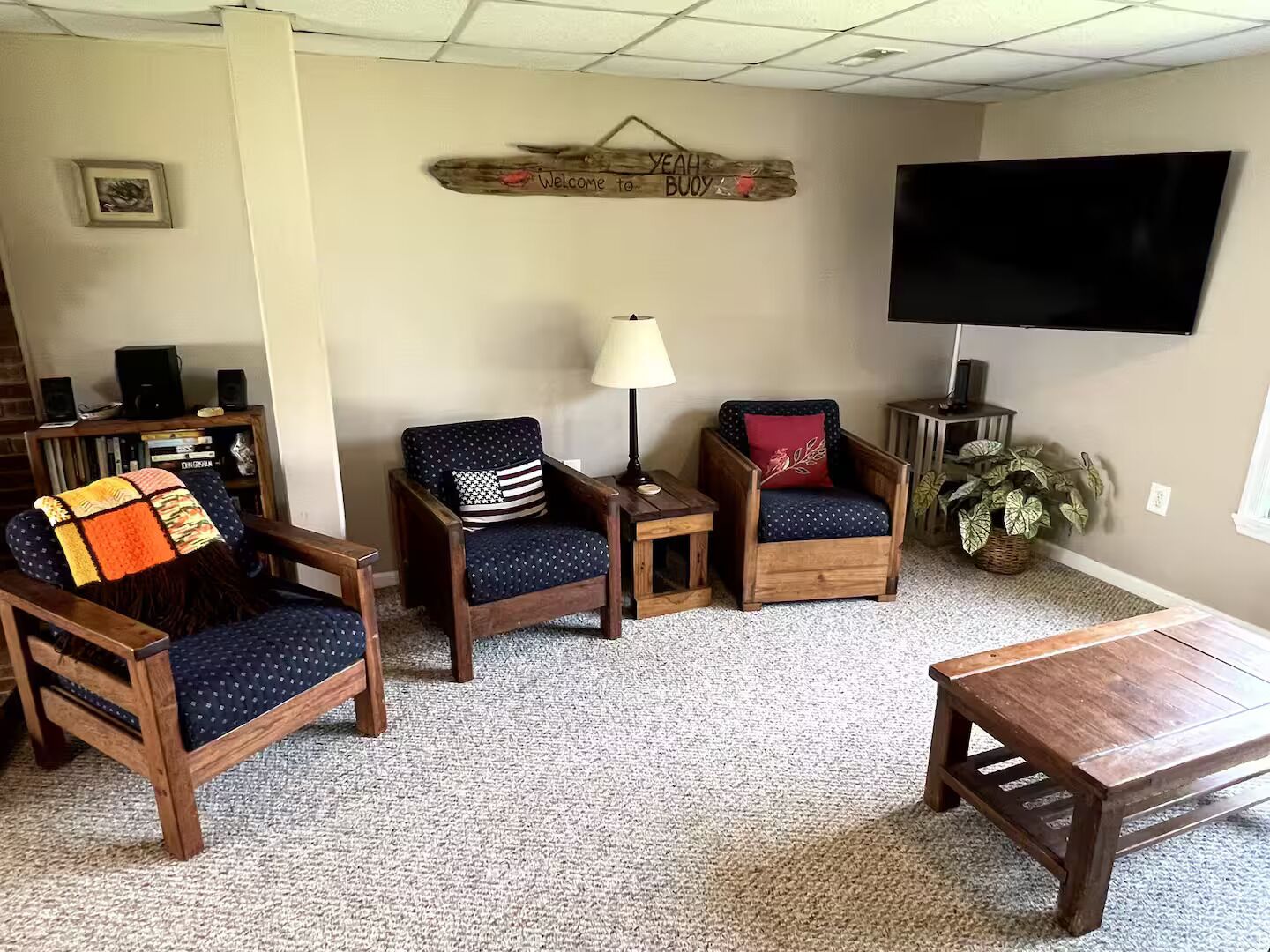 A living room with two wooden chairs, a small table, a TV, and a bookshelf.