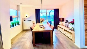 Un comedor moderno con una mesa de madera, sillas y vistas amplias por las ventanas.
