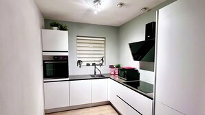 Una cocina moderna con armarios blancos, estufa negra y ventana con persianas.