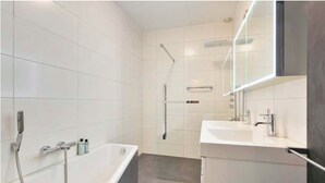 Un baño moderno con bañera, ducha y tocador con espejo.