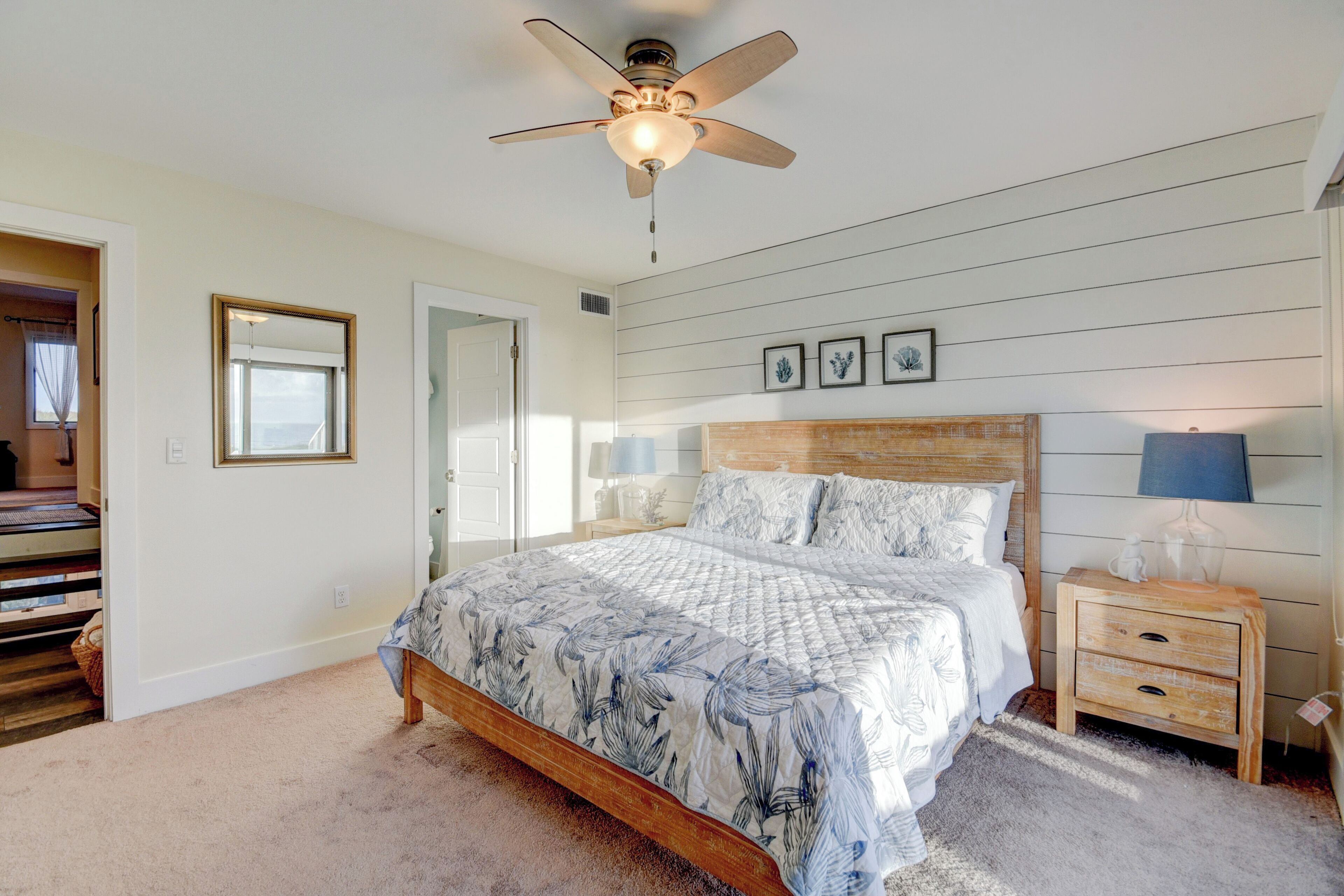 A bedroom with a wooden bed, a nightstand with a lamp, and a ceiling fan.