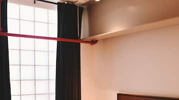 Una habitación de hotel con cama, mesita de noche, lámpara y ventana con cortinas.