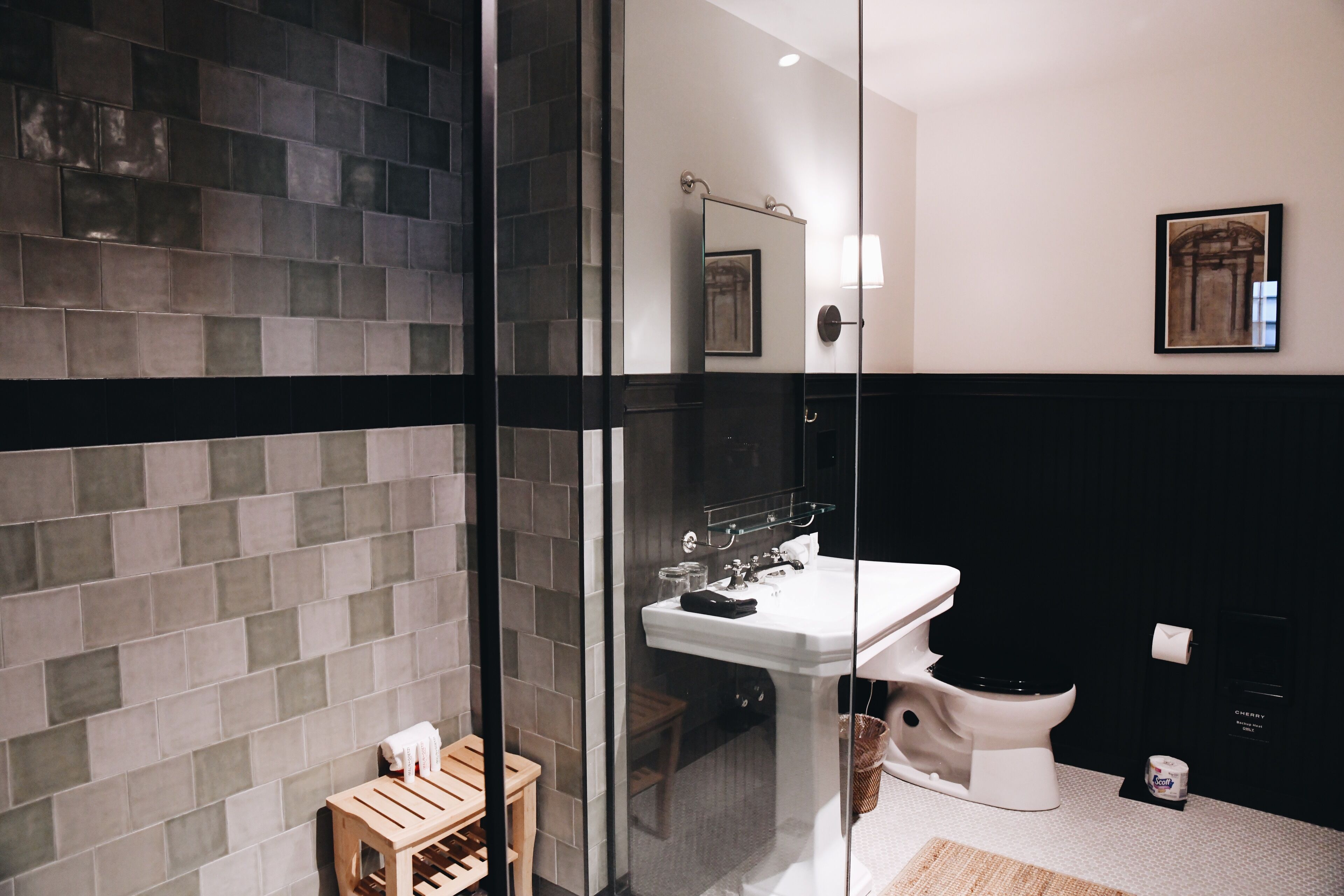 A modern bathroom with a glass shower enclosure, a white sink, and a black toilet.