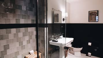 Et moderne badeværelse med en glas brusekabine, en hvid vask og et sort toilet.