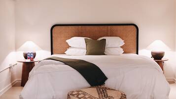 A modern hotel room with a large bed, a bedside table with a lamp, and a decorative pillow.