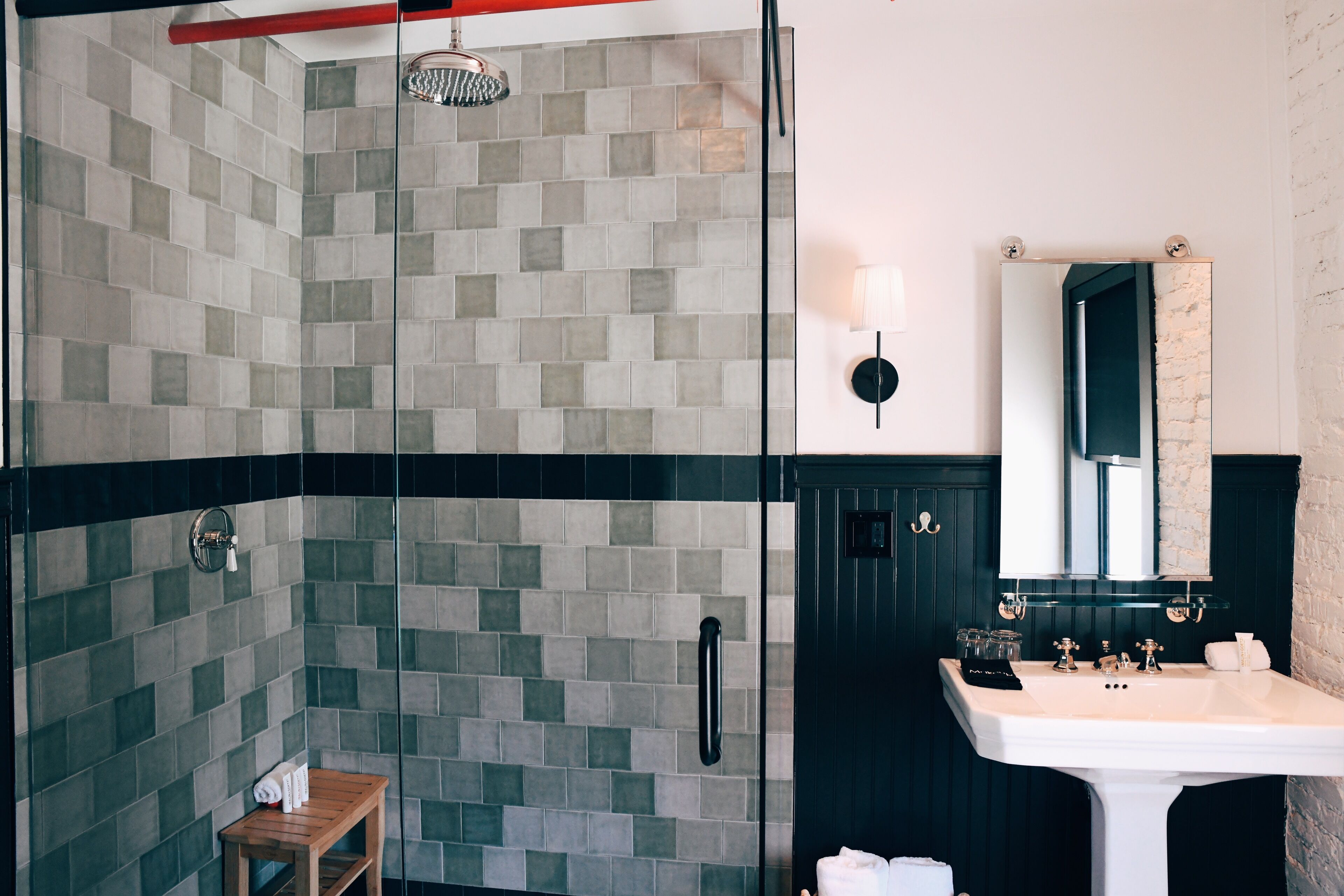 Une salle de bain avec une douche carrelée, un lavabo et un miroir.