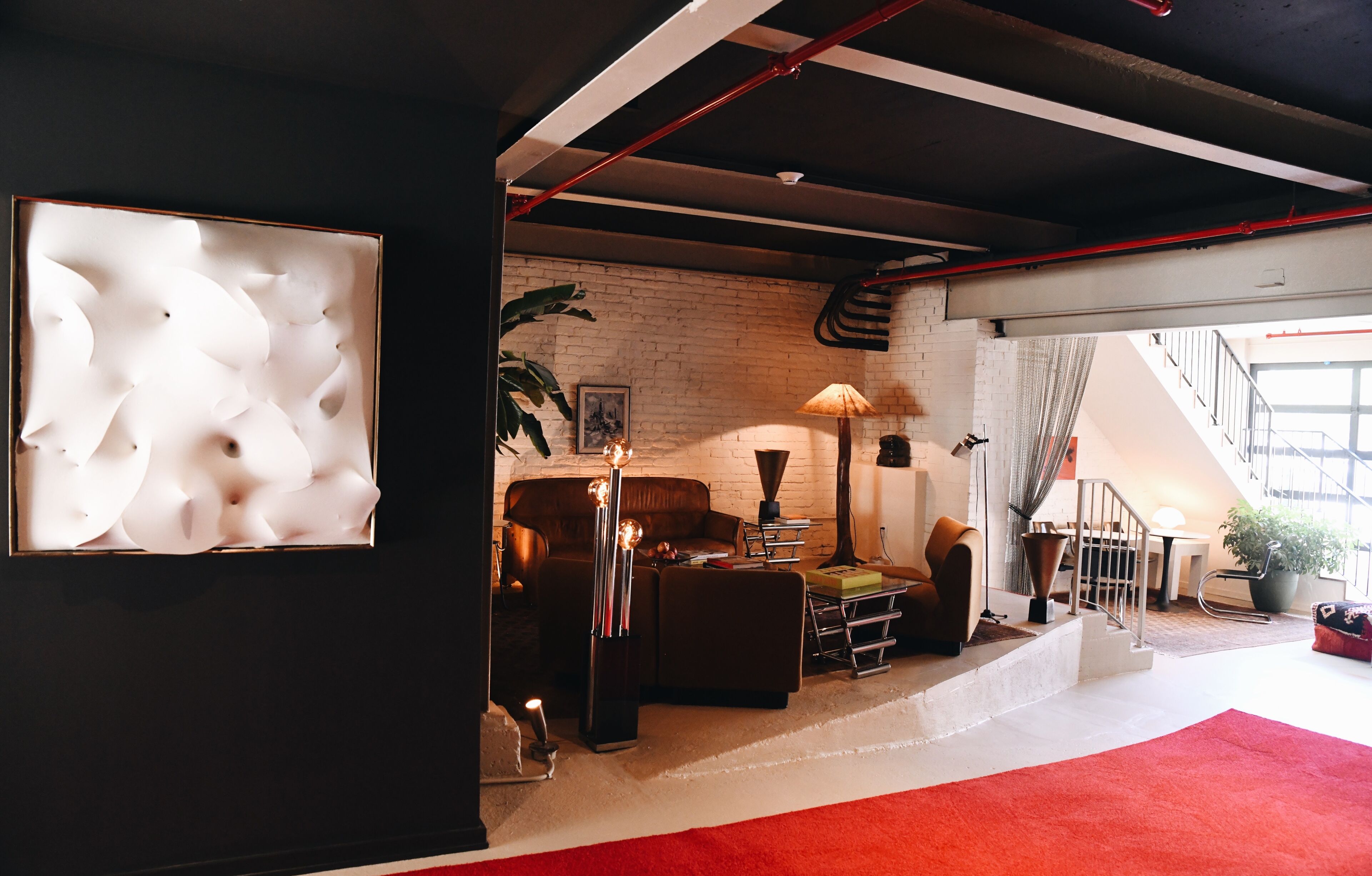 Una sala de estar moderna con pared de ladrillo, sofá de cuero y alfombra roja.
