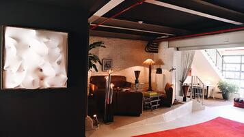Una sala de estar moderna con pared de ladrillo, sofá de cuero y alfombra roja.