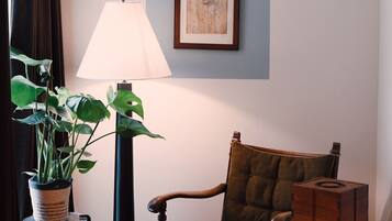 Une pièce comprenant une chaise, une lampe, une table, un tableau encadré et une plante en pot.