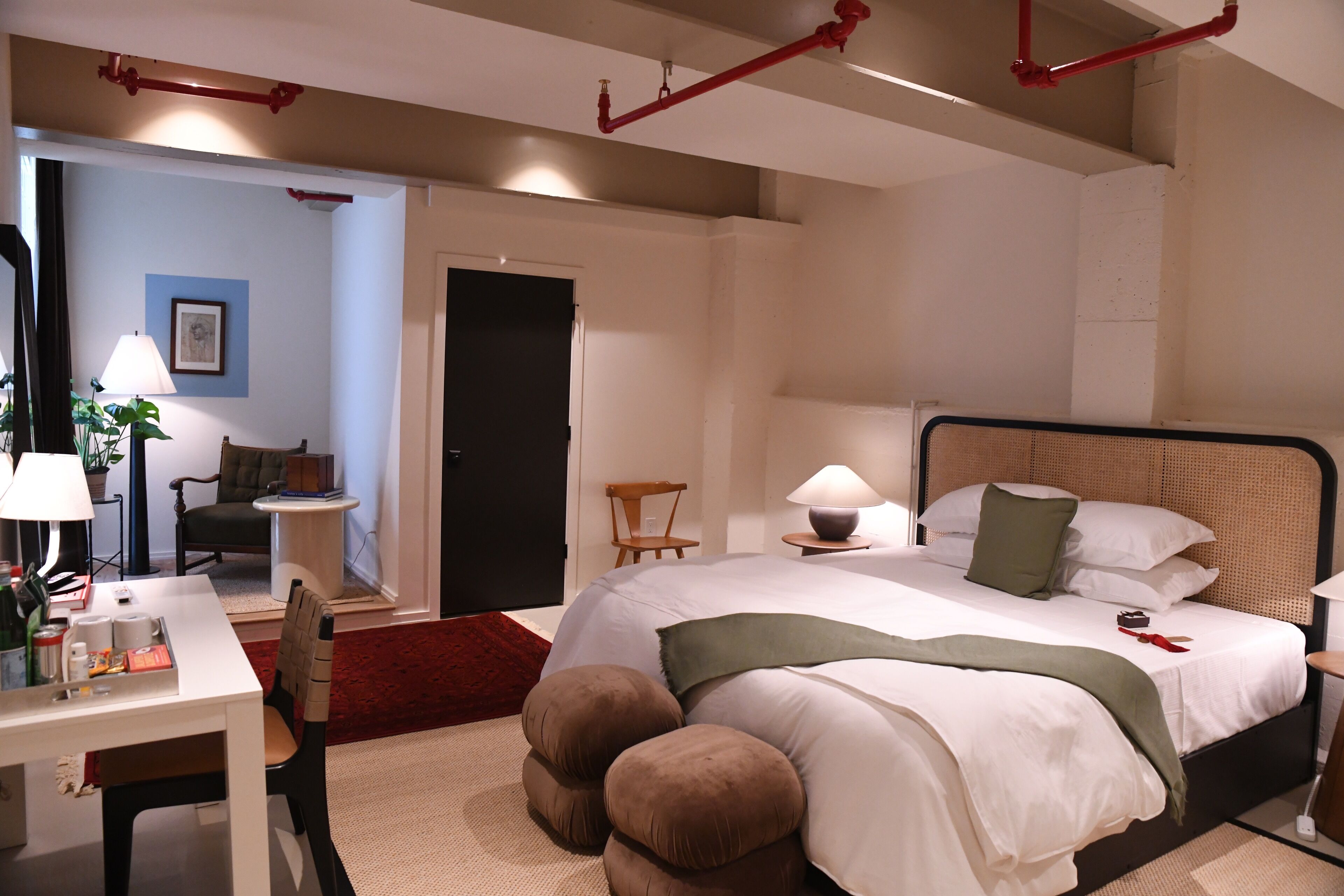 A bedroom with a bed, bedside table, lamp, chair, and a desk with a chair.