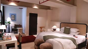 A bedroom with a bed, bedside table, lamp, chair, and a desk with a chair.