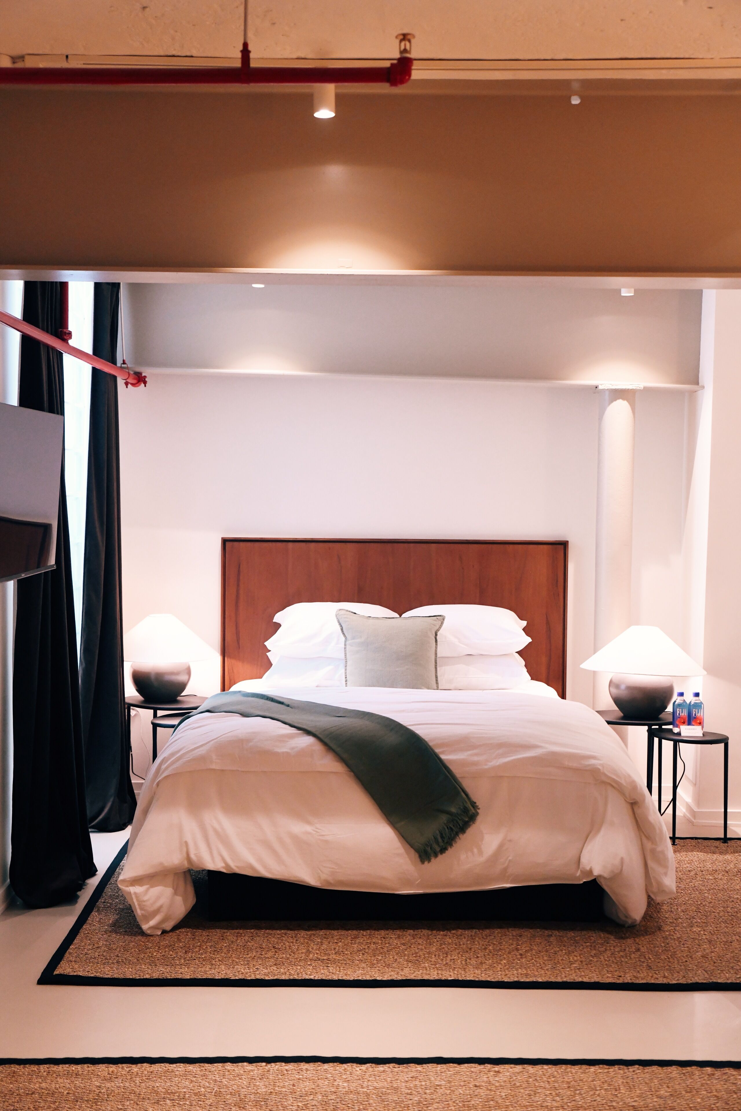 Et moderne hotelværelse med en stor seng, to sengeborde og et fjernsyn på væggen.