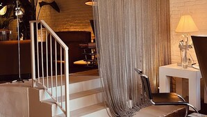 A modern interior with a staircase, a patterned curtain, and a chandelier.