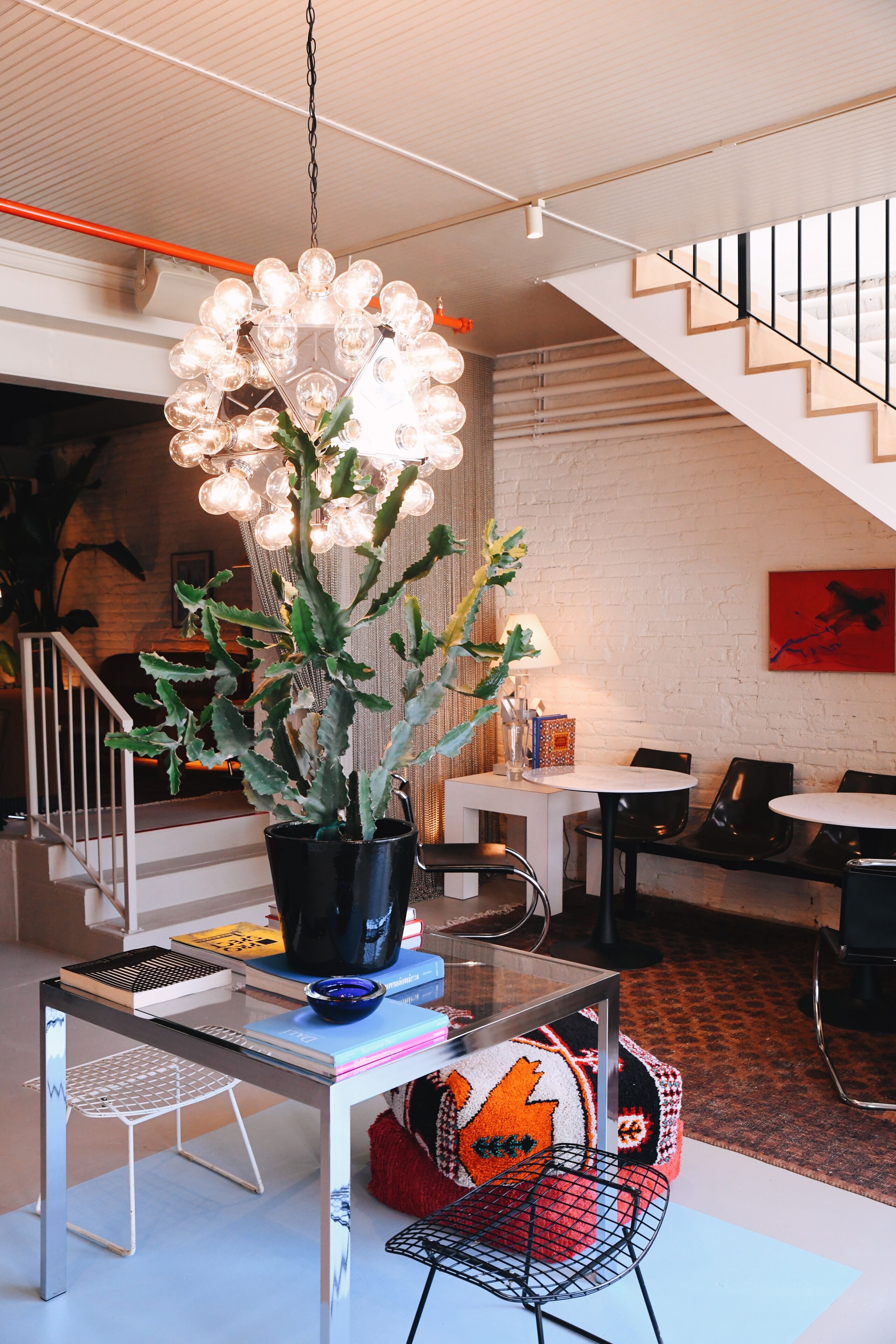 A modern living room with a staircase, a potted plant, a coffee table, and a hanging light fixture.
