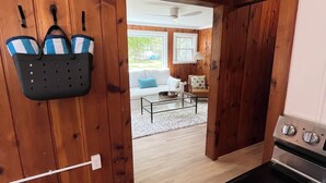 A kitchen with wooden walls, a stove, and a hanging basket with towels. - Charming Lake Huron cottage (Tawas City)