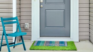 A gray front door with a white frame, a blue chair to the left, and a green doormat with a welcome message. - NEW Putt Chip&Chill 3BRTownhouse NMB SportsComplex (little river)