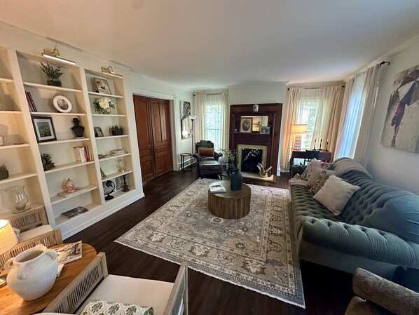 A living room with a sofa, a coffee table, a fireplace, and a bookshelf.