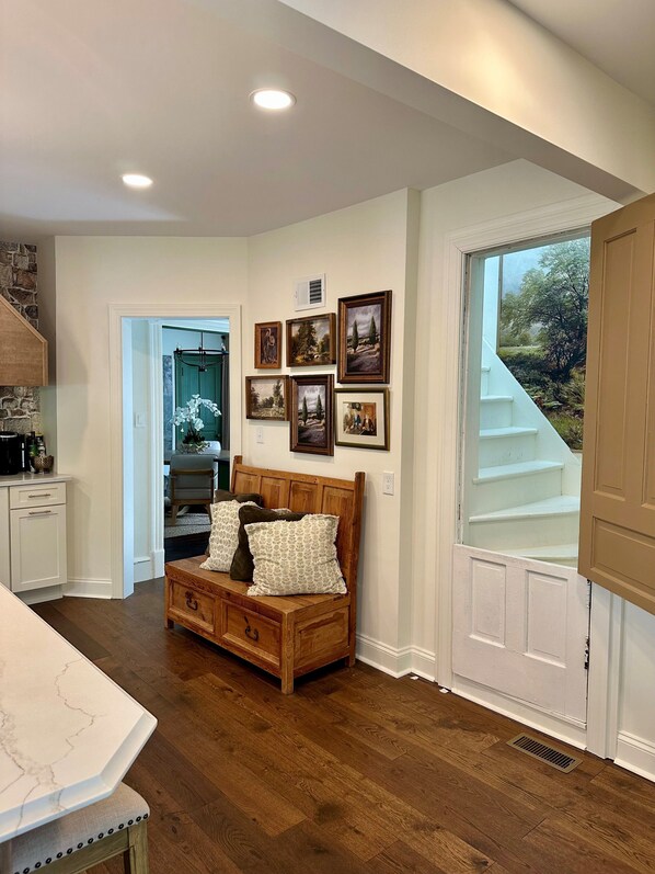 Une chambre avec un lit en bois, une table de chevet et une commode. Des tableaux encadrés ornent le mur, et une fenêtre offre une vue sur l’extérieur.